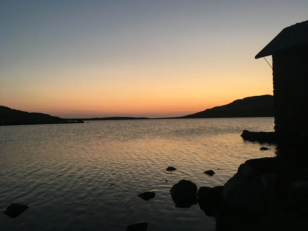 Evening light over a mountain lake with a boathouse on the shore