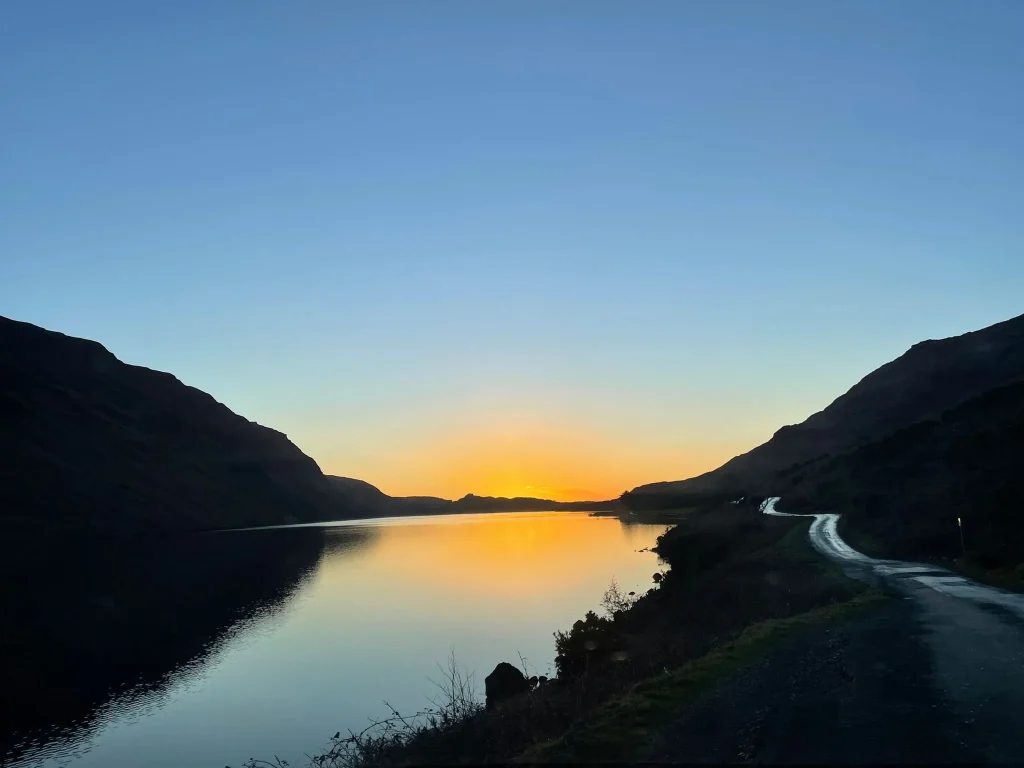 Sunrise glow over a quiet lake surrounded by hills