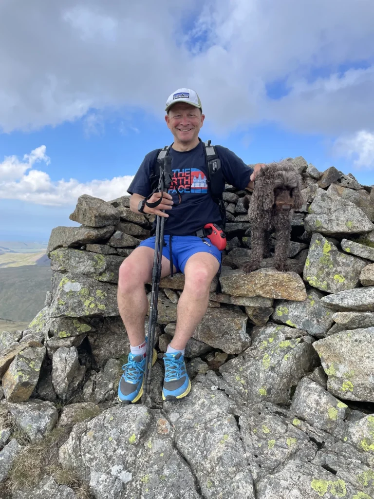 Hiker and dog sitting on a Lake District mountain summit