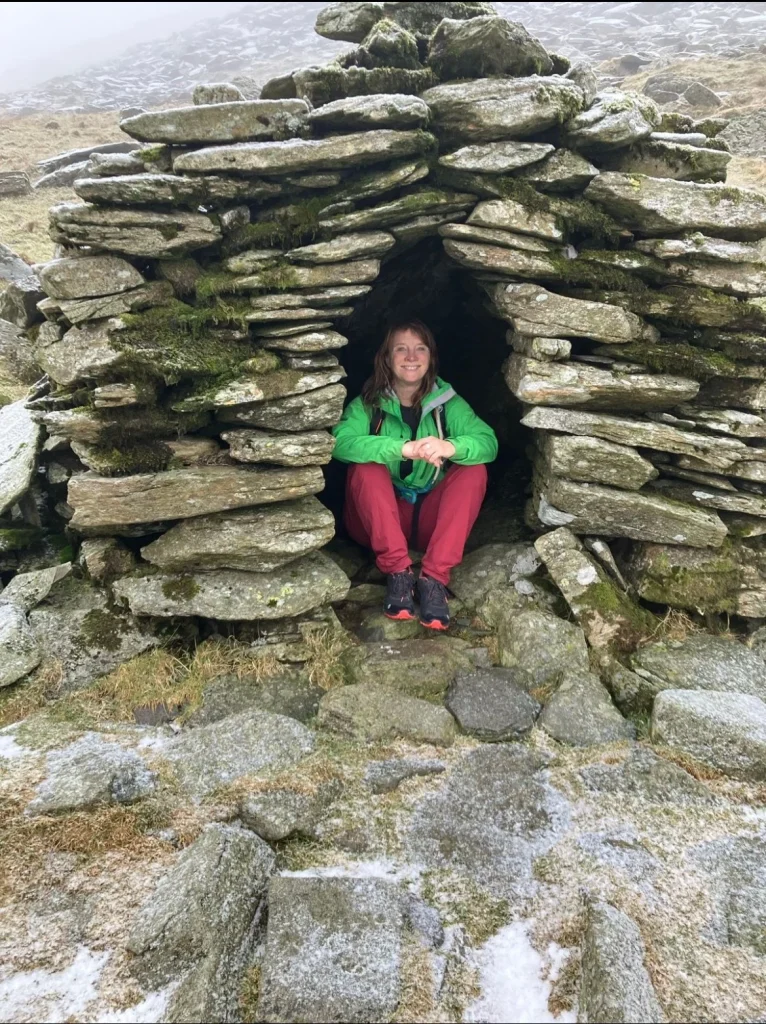 Ros sitting in an old miners’ stone shelter at Coniston Coppermines