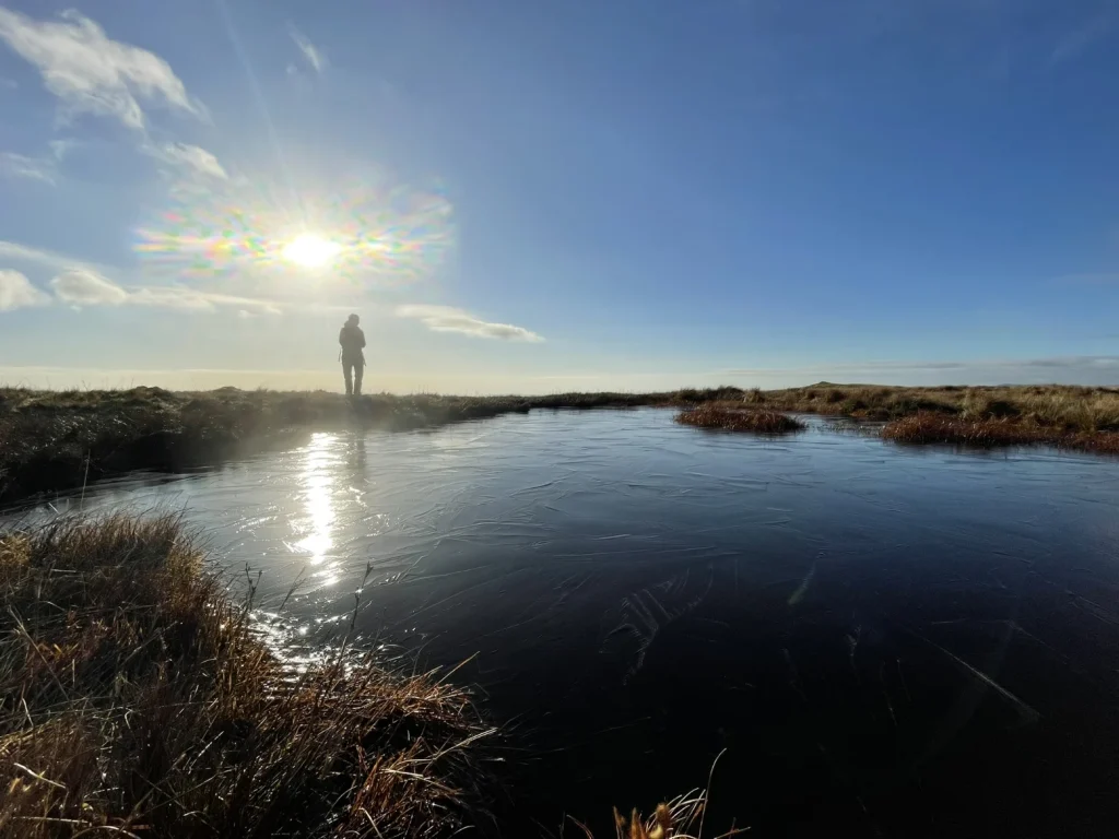 Winter sunshine over a frozen tarn on a Lake District hill