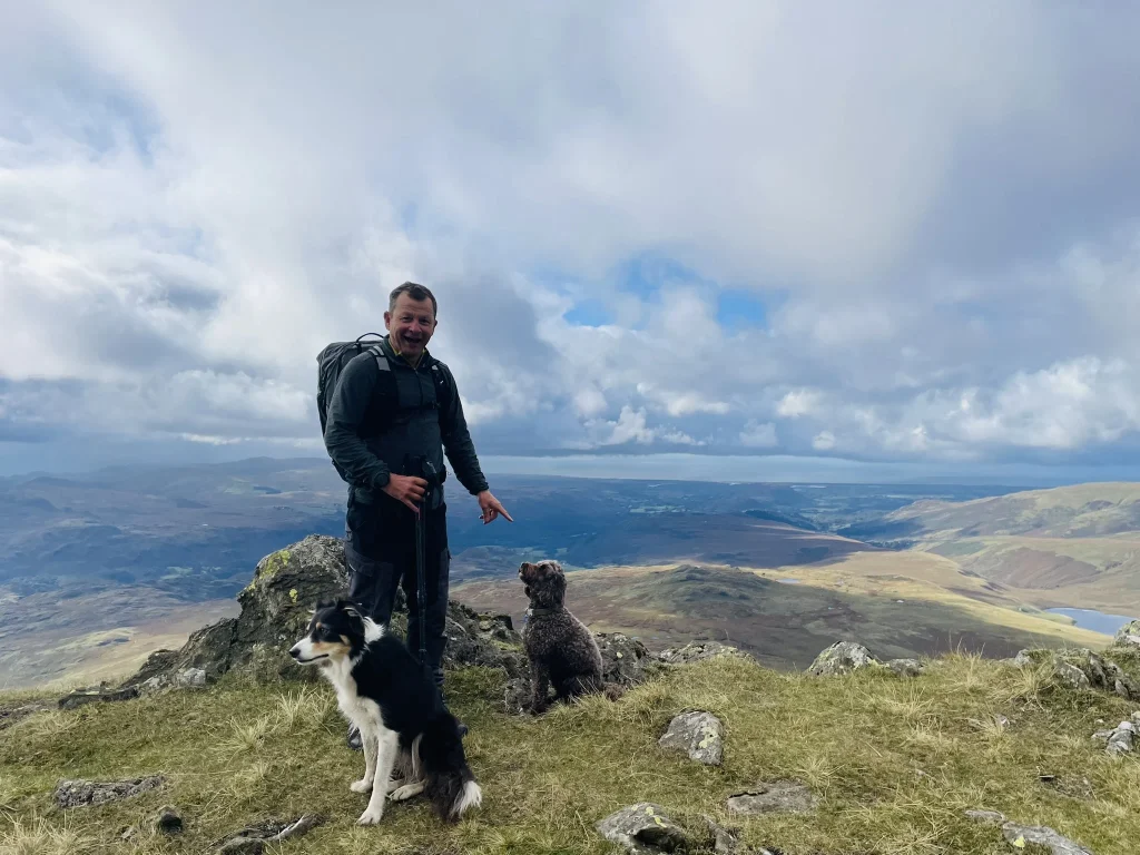 Walker with Blea and another dog on summit above Eskdale near Scafell and Slight Side