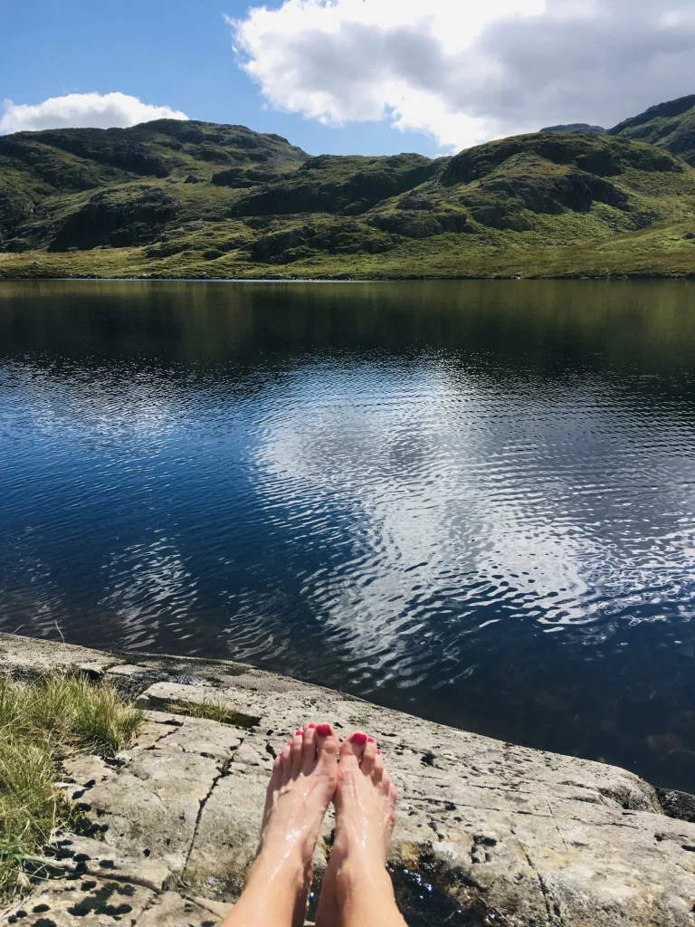 Feet by the water at Styhead Tarn in the Lake District fells