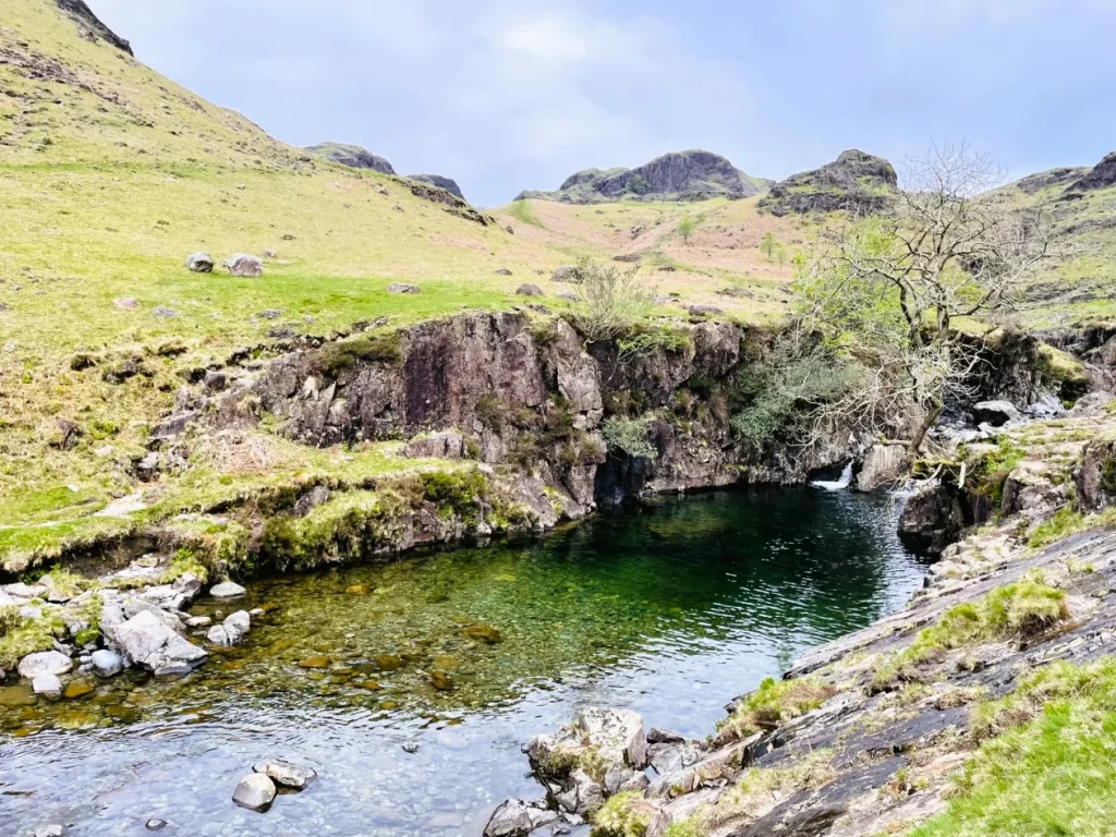 Rocky river pool in Upper Eskdale surrounded by green fells in the Western Lake District
