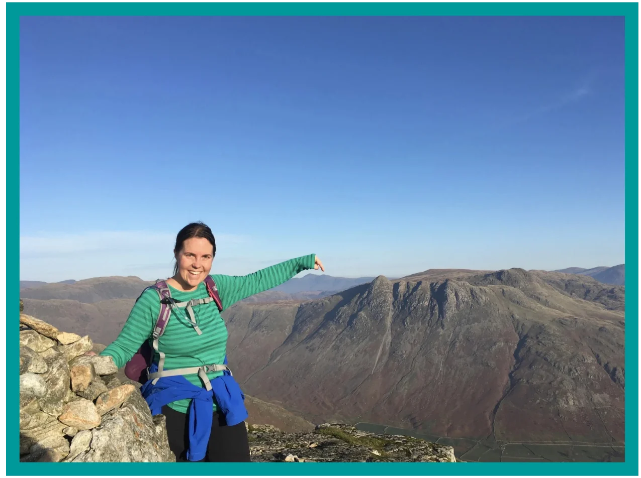 Walker pointing towards mountain ridges during a bespoke walk in the Lake District